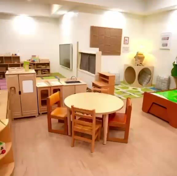 Classroom with a round table, wooden chairs and play kitchen